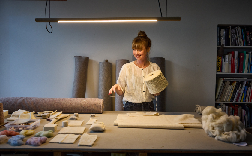 Foto van Christien Meinderstsma in een atelier, omringt door producten van wol