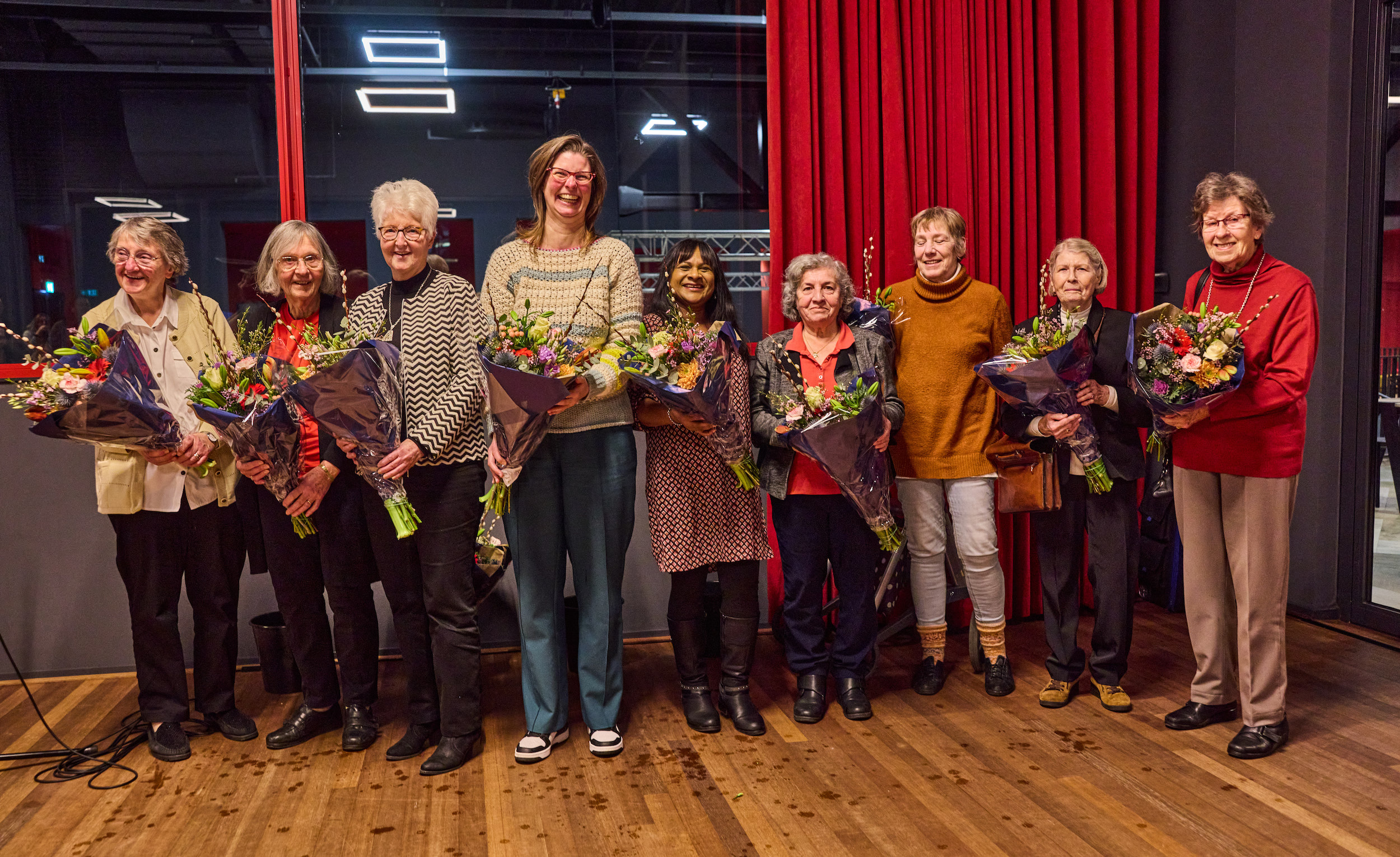 De vrijwilligers uit de wijken Pernis en Pendrecht op een rij met ieder een boeket bloemen